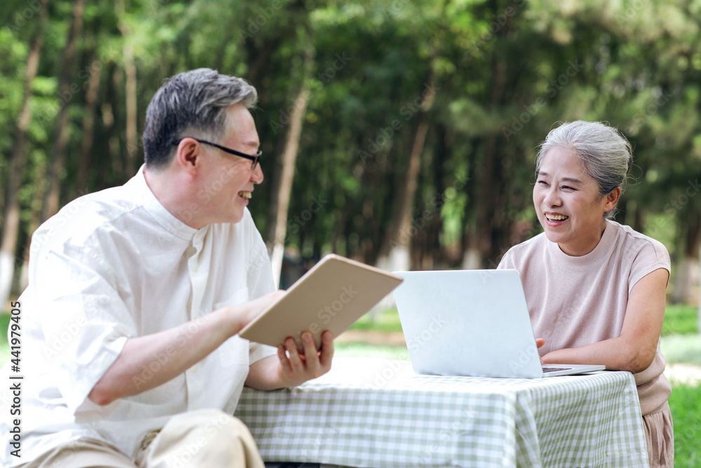 Happy old couple use computer to surf the Internet outdoors Happy old couple use computer to surf the Internet outdoors