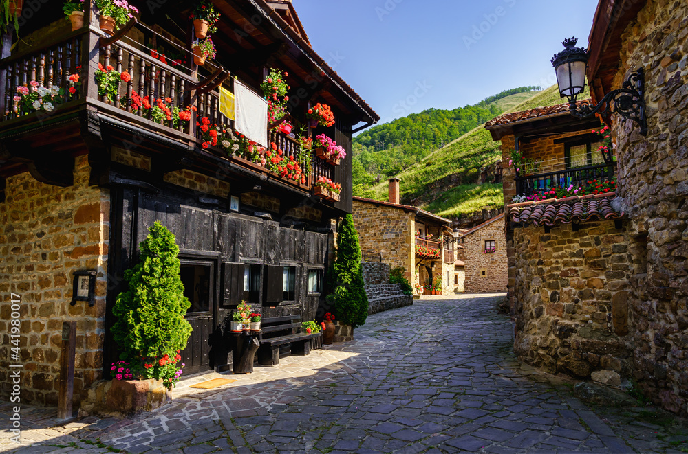 Picturesque stone houses with black wooden facade and narrow stone alley. Barcena Mayor Santander.