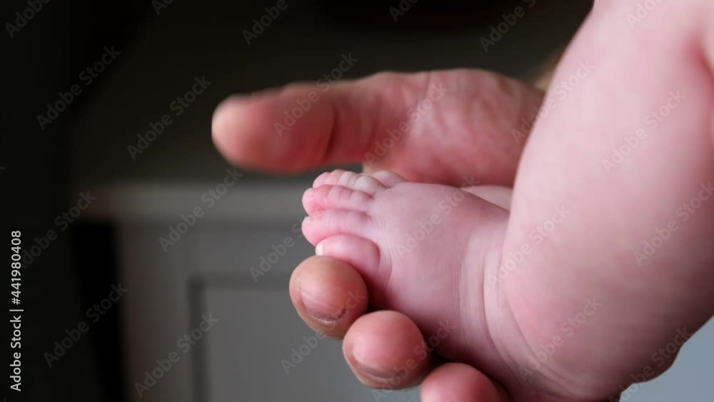 Father holding Baby Feet in Hands. Legs Newborn in male parents Hand. Small children's Feet in the Father's Palm. Close-up. Little Toes of Child and Man Hands of Happy Parent. Father's Day Holiday. Father holding Baby Feet in Hands. Legs Newborn in male parents Hand. Small children's Feet in the Father's Palm. Close-up. Little Toes of Child and Man Hands of Happy Parent. Father's Day Holiday.