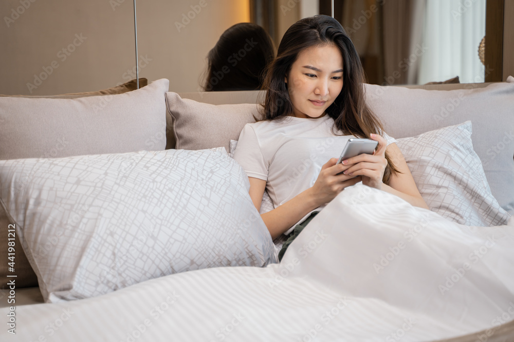 happy Young asian woman holding cellphone in bed technology lifestyle concept happy Young asian woman holding cellphone in bed technology lifestyle concept