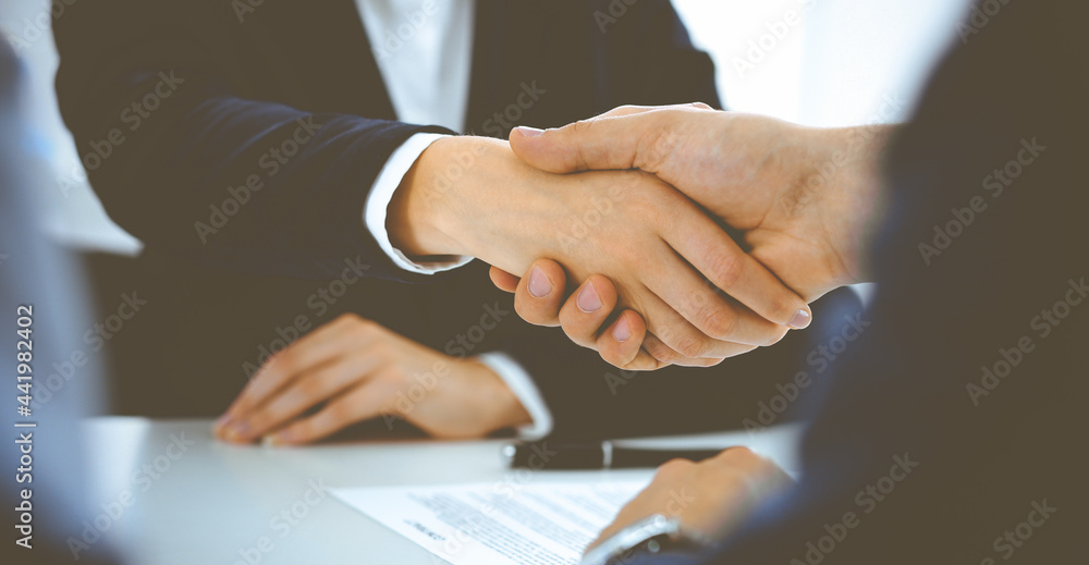 Businesspeople or lawyers shaking hands finishing up a meeting in blue toned office , close-up. Success at negotiation and handshake concepts Businesspeople or lawyers shaking hands finishing up a meeting in blue toned office , close-up. Success at negotiation and handshake concepts