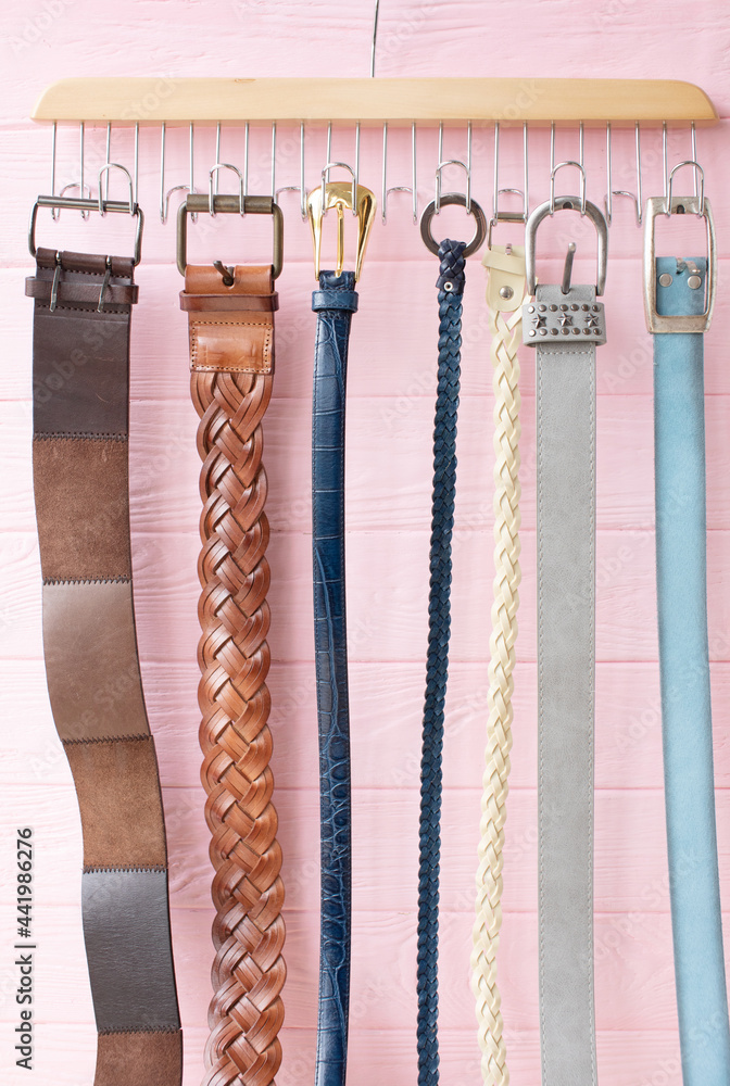 Leather belts in different colours for jeans and chinos on the wooden surface. Leather belts in different colours for jeans and chinos on the wooden surface.