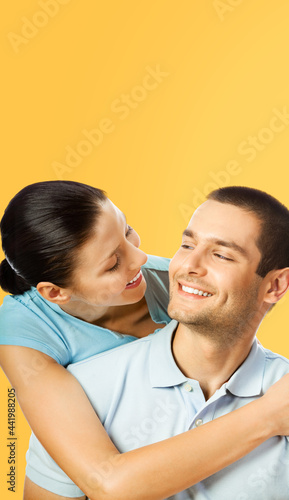 Smiling happy amazed couple. Portrait image of standing close models in love studio concept, isolated over orange yellow colour background. Young man and woman posing together. Copy space.