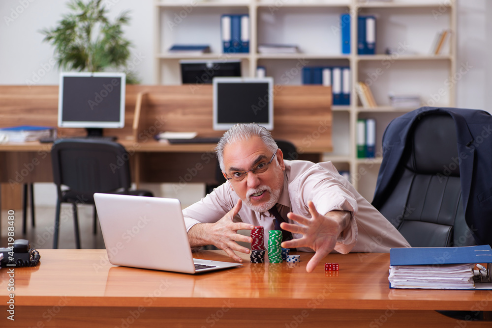 Old male employee in gambling concept at workplace Old male employee in gambling concept at workplace