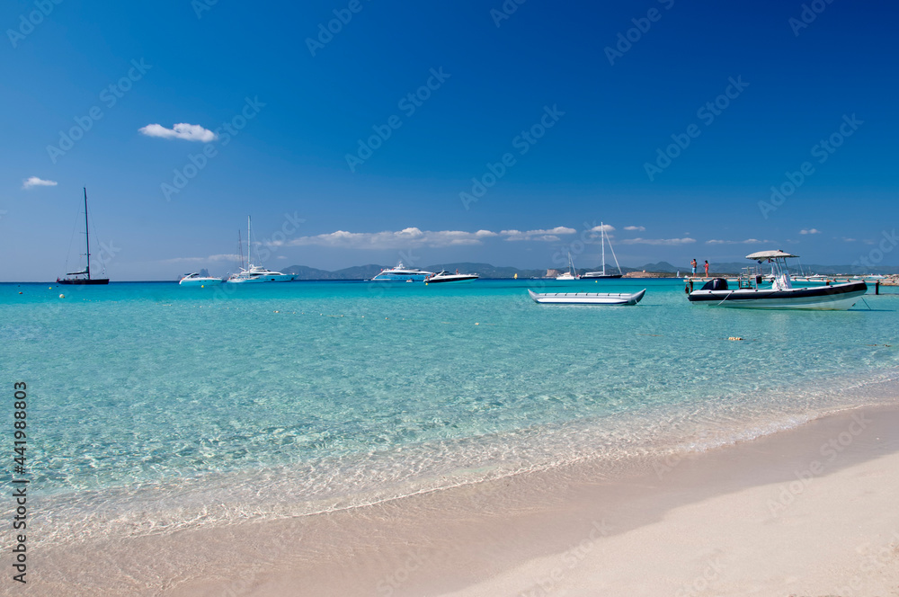 Ses Illetes Beach on the island of Formentera, Spain. In the background anchored boats and the blue sky