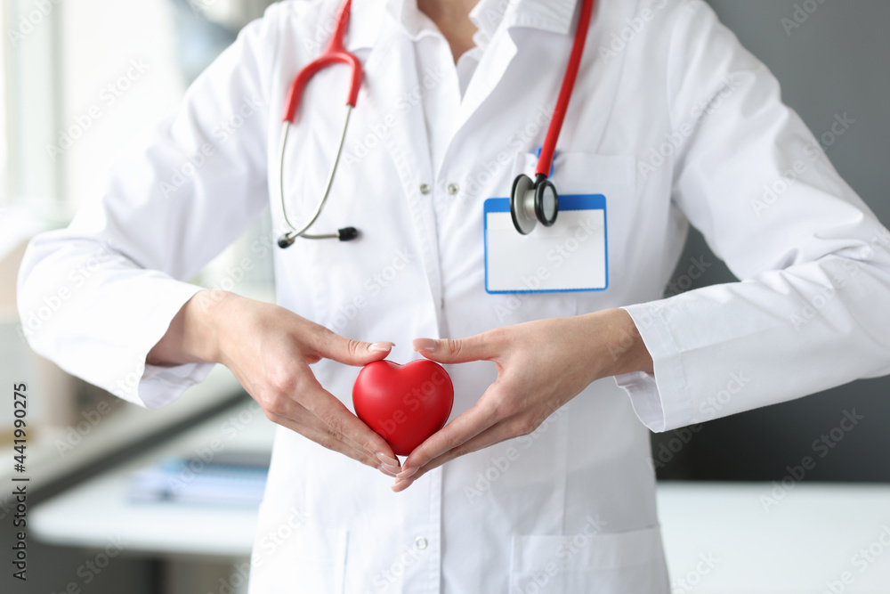 Doctor holding red toy heart in his hands in clinic closeup Doctor holding red toy heart in his hands in clinic closeup