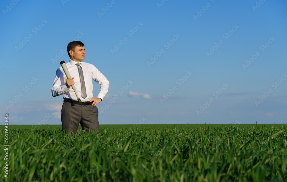 businessman poses with a spyglass, he looks into the distance and looks for something, green grass and blue sky as background businessman poses with a spyglass, he looks into the distance and looks for something, green grass and blue sky as background