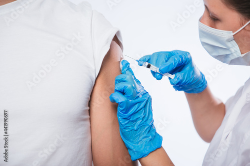 Girl doctor holds a syringe and makes an injection to a patient in a medical mask. Covid-19 or coronavirus vaccine. Masked man receiving coronavirus vaccination graft photo
