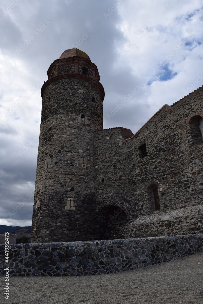 Castillo de época medieval de piedra con torre alta en un día nublado con cielo azul de fondo