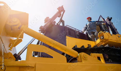 Industrial portrait of working man, excavator driver climbs into cab to perform work on construction site
