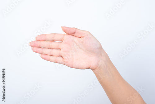 Woman's hand with pink manicure over isolated white background pointing aside with the palm of the hand, indicating to the left. 