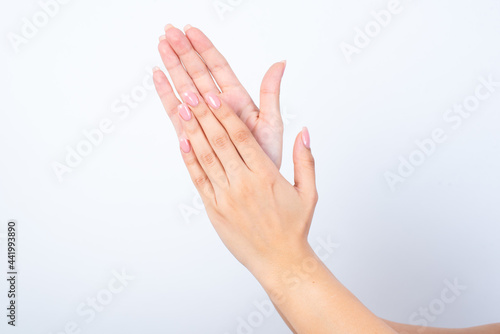 Woman's hands with pink manicure over isolated white background  clapping.  © Roquillo