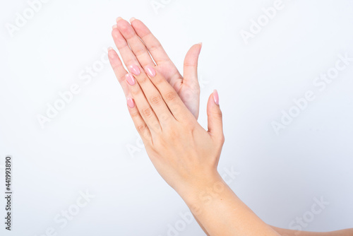 Woman's hands with pink manicure over isolated white background clapping. 