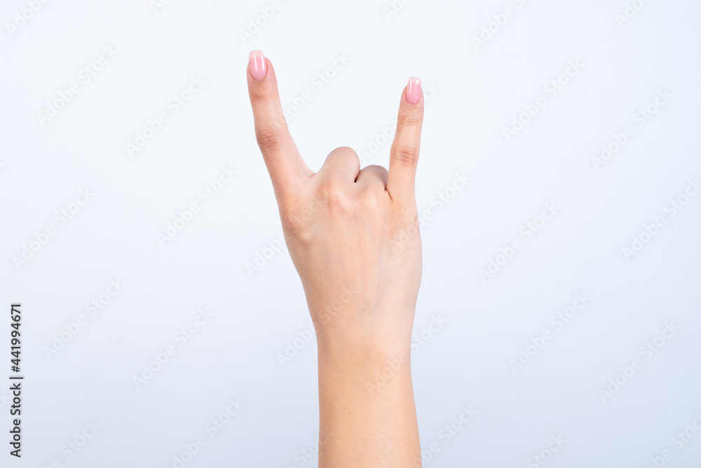 Isolated woman's hand gesturing up with hand rock and roll, horn sign. Back side of the hand. Isolated woman's hand gesturing up with hand rock and roll, horn sign. Back side of the hand.