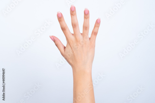hands with pink manicure over white background showing with fingers number five. Back side of the hand.