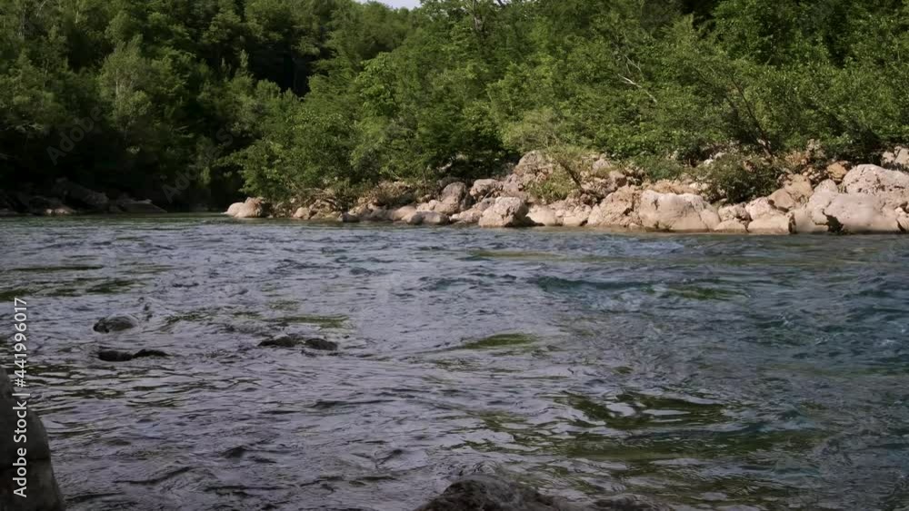 Horizontal zoomed 4k slow motion video. Beautiful stormy mountain river of bluish hue in gorge among large stones. Dense green deciduous forest in background. Horizontal zoomed 4k slow motion video. Beautiful stormy mountain river of bluish hue in gorge among large stones. Dense green deciduous forest in background.