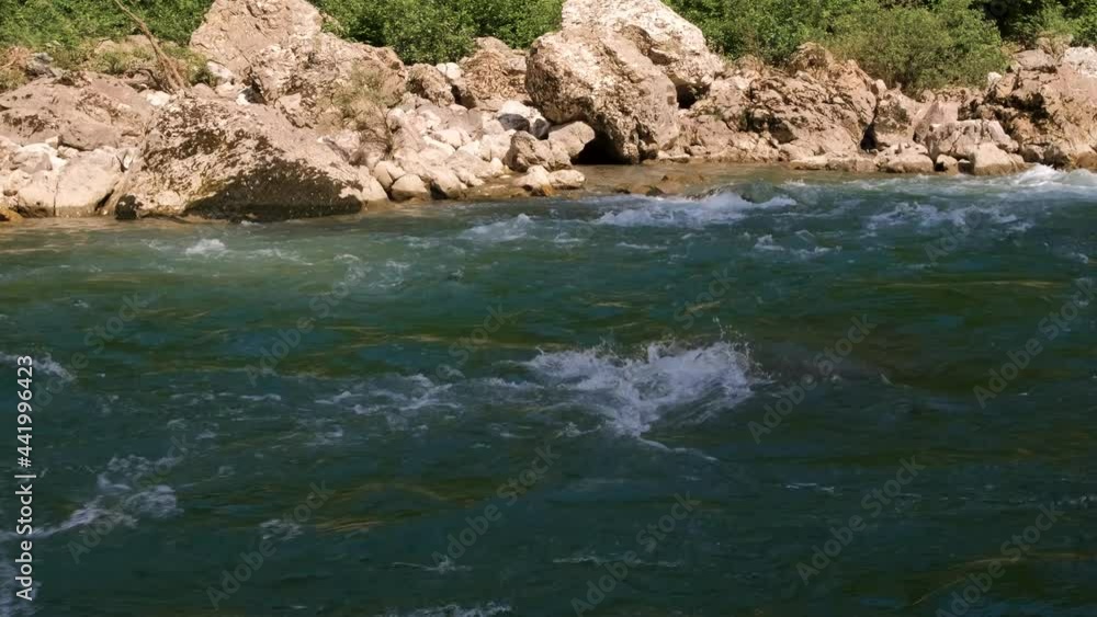Horizontal zoomed 4k slow motion video. Beautiful stormy mountain river of bluish hue in gorge among large stones. Dense green deciduous forest in background. Horizontal zoomed 4k slow motion video. Beautiful stormy mountain river of bluish hue in gorge among large stones. Dense green deciduous forest in background.