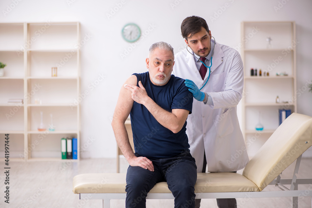 Old male patient visiting young male doctor in vaccination conce Old male patient visiting young male doctor in vaccination conce