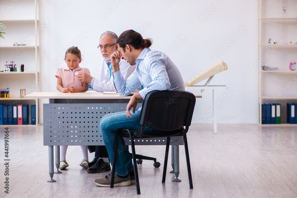 Small girl with her father visiting old male doctor Small girl with her father visiting old male doctor