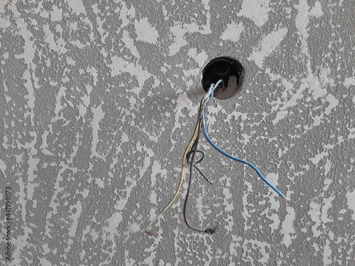 One hole for an electrical outlet with wires on a freshly putty wall. Modern textured putty.