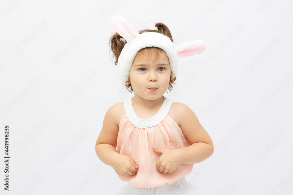 Charming girl in dress and white ears posing as cute bunny on gray background Charming girl in dress and white ears posing as cute bunny on gray background