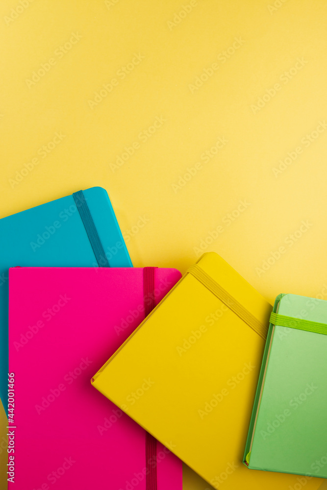 Flat lay with four notebooks colors blue, pink, yellow and green about on yellow background. Set of school equipment. Flat lay with four notebooks colors blue, pink, yellow and green about on yellow background. Set of school equipment.