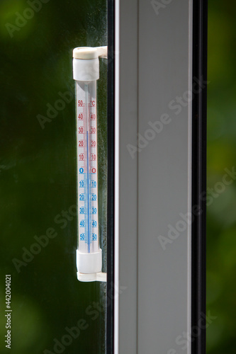 A Celsius thermometer on a window frame shows high temperatures of 32 degrees during an heat outside.