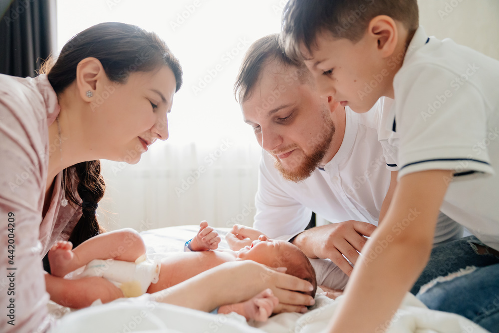 first day of newborn at home. Happy family looking at the newborn in the bedroom first day of newborn at home. Happy family looking at the newborn in the bedroom