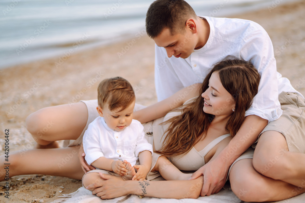 Young family on the beach. People are having fun on summer vacation. Father, mother and child against the background of the blue sea and sky. Travel, active lifestyle, vacation, rest concept.