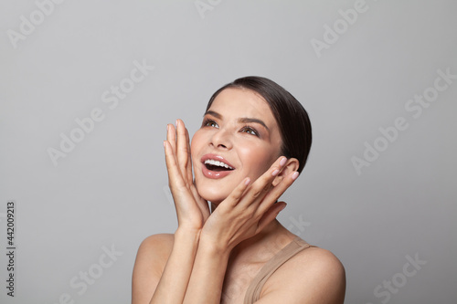 Beautiful excited surprised woman with open mouth, studio portrait on white background