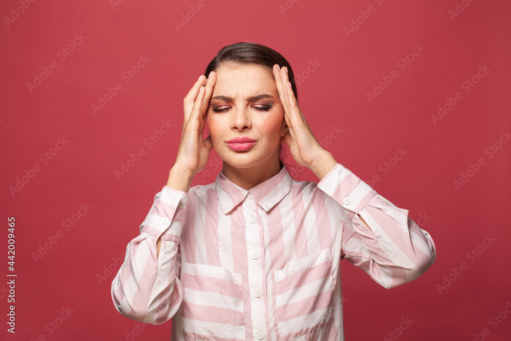 Young brunette woman suffering from headache desperate and stressed because pain and migraine on red background. Hands on head Young brunette woman suffering from headache desperate and stressed because pain and migraine on red background. Hands on head