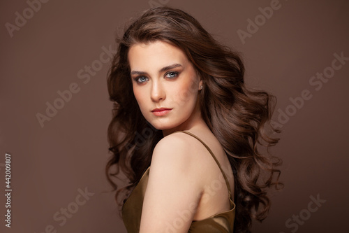 Natural woman with healthy wavy hair. Beauty female model with makeup and curly hairstyle