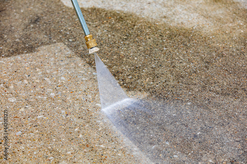Pressure washing concrete driveway. Home cleaning, maintenance and household chores concept photo