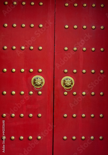 Red door with lion heads in asian style. © Serazetdinov