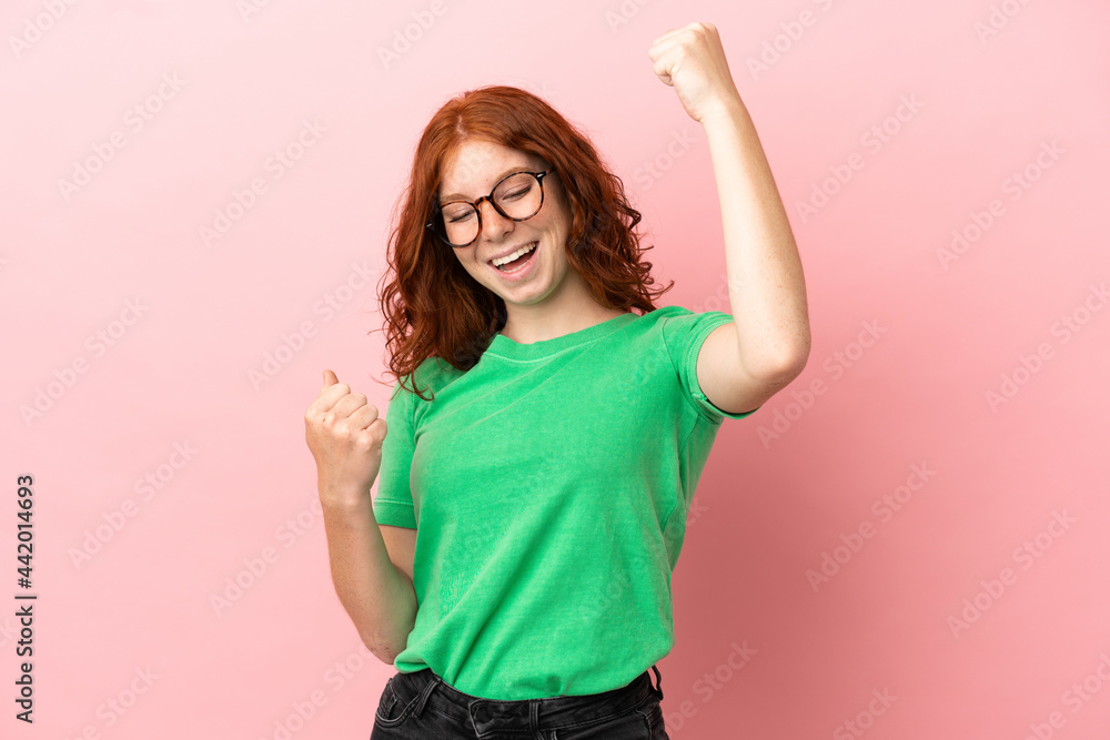 Teenager redhead girl over isolated pink background celebrating a victory