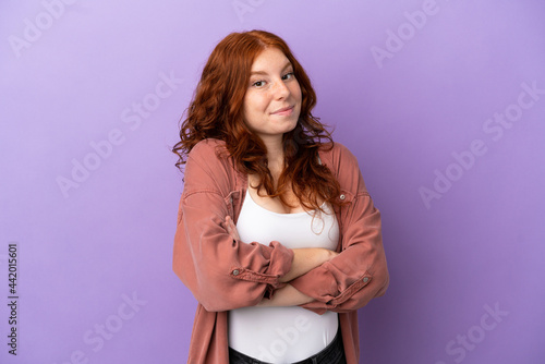 Teenager redhead girl over isolated purple background making doubts gesture while lifting the shoulders