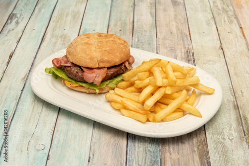 Classic beef burger with cheese, lettuce and bacon and guranicion of French fries