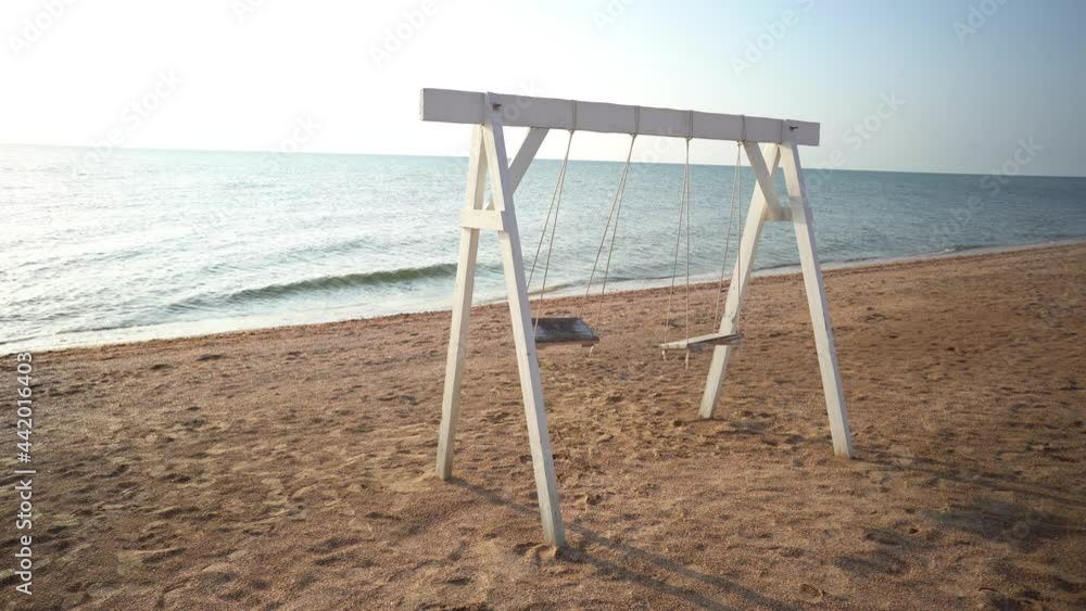 Swings with a wooden seats against the blue sea. Swings with a wooden seats against the blue sea.