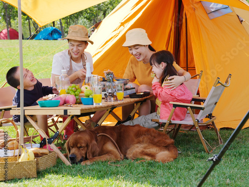 Happy family of four and pet dog have a picnic outdoors