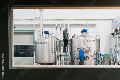 Workers interacting near lauter tun in brewery