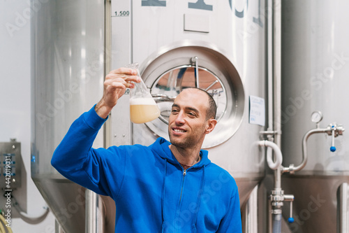 Smiling brewer with wort in flask in factory photo