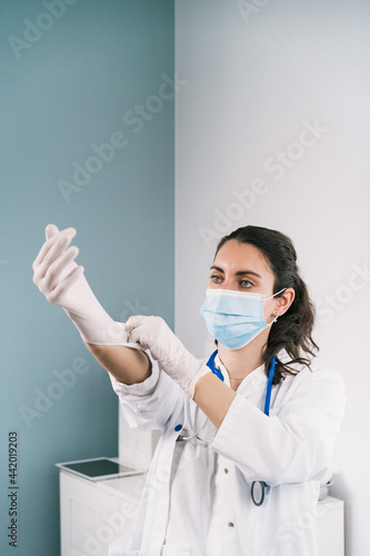 Physician putting on latex glove at work in clinic photo