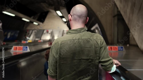 Drunk man standing on the escalator going down at London Bridge Jubilee line underground station