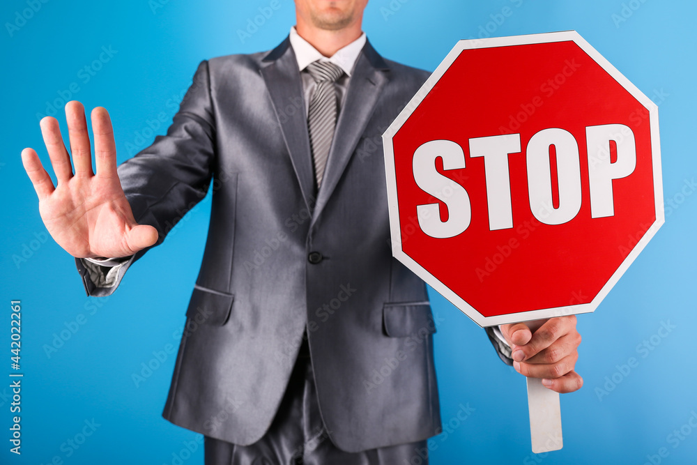 businessman holding a stop sign on a blue background. man in a jacket holding a stop sign businessman holding a stop sign on a blue background. man in a jacket holding a stop sign