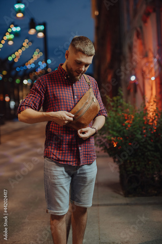 Man with waist bag walks in a night city