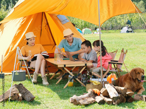 Happy family of four and dog camping out