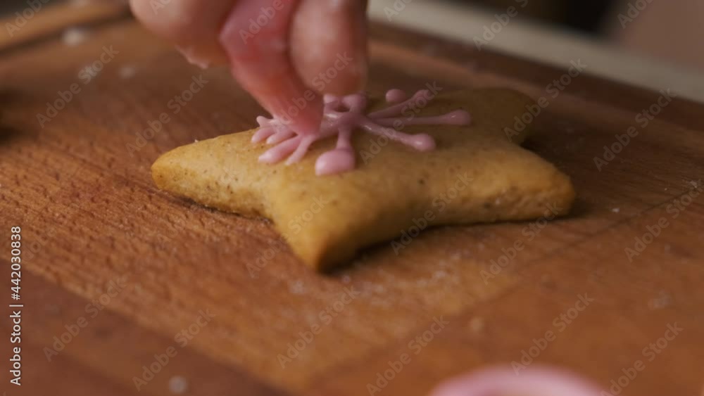 Close up woman hand decorating Christmas gingerbread in the shape of star with icing on the wooden desk. Preparation to the holidays. Close up woman hand decorating Christmas gingerbread in the shape of star with icing on the wooden desk. Preparation to the holidays.