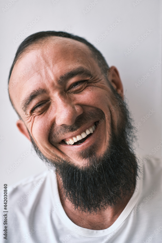 Happy muslim man with beard dressed in white t-shirt is laughing. human emotions. Looking at camera Happy muslim man with beard dressed in white t-shirt is laughing. human emotions. Looking at camera
