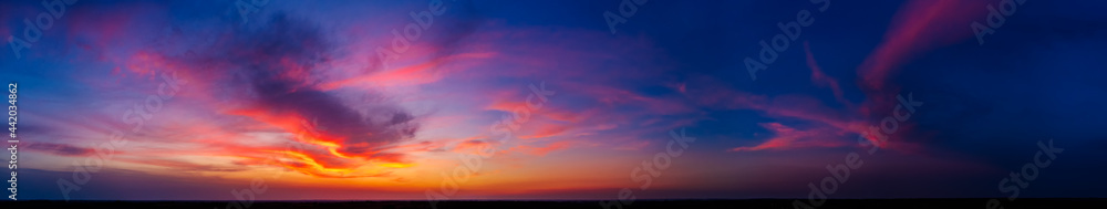 Dramatic wide panorama of late sunset with burning sky