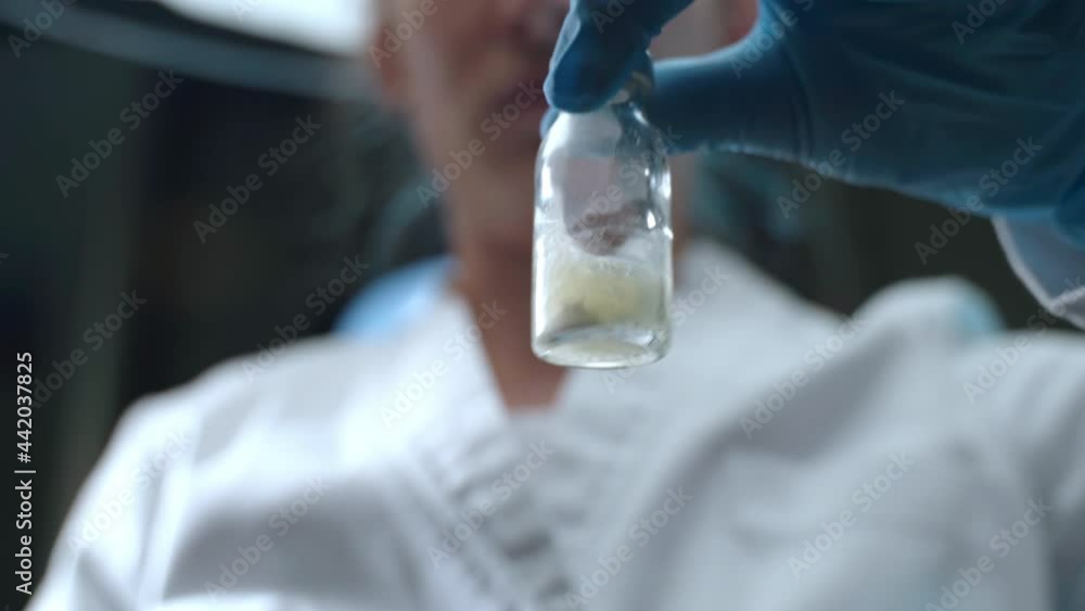 Low angle view of potential vaccine vial in laboratory researcher's hands, professional virologist shaking vial and watching compound reaction. Chemical experiments with elements and solutions Low angle view of potential vaccine vial in laboratory researcher's hands, professional virologist shaking vial and watching compound reaction. Chemical experiments with elements and solutions
